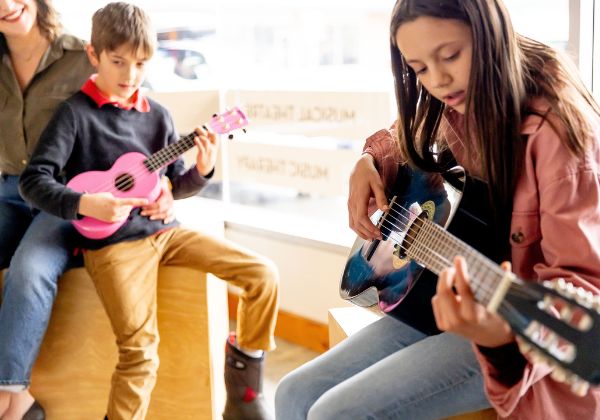 Students playing guitar together in an ensemble at SAM